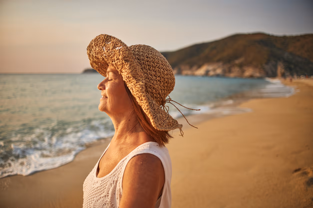 Woman on beach enjoying warm sun on face