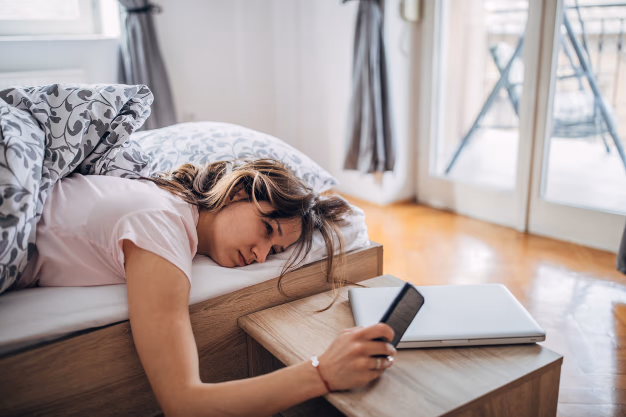 Woman looking at phone first thing in the morning after poor sleep