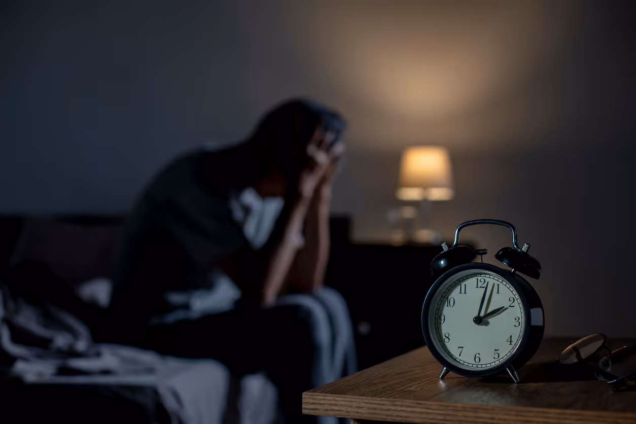 Man sitting on side of bed at 2am because he cant sleep