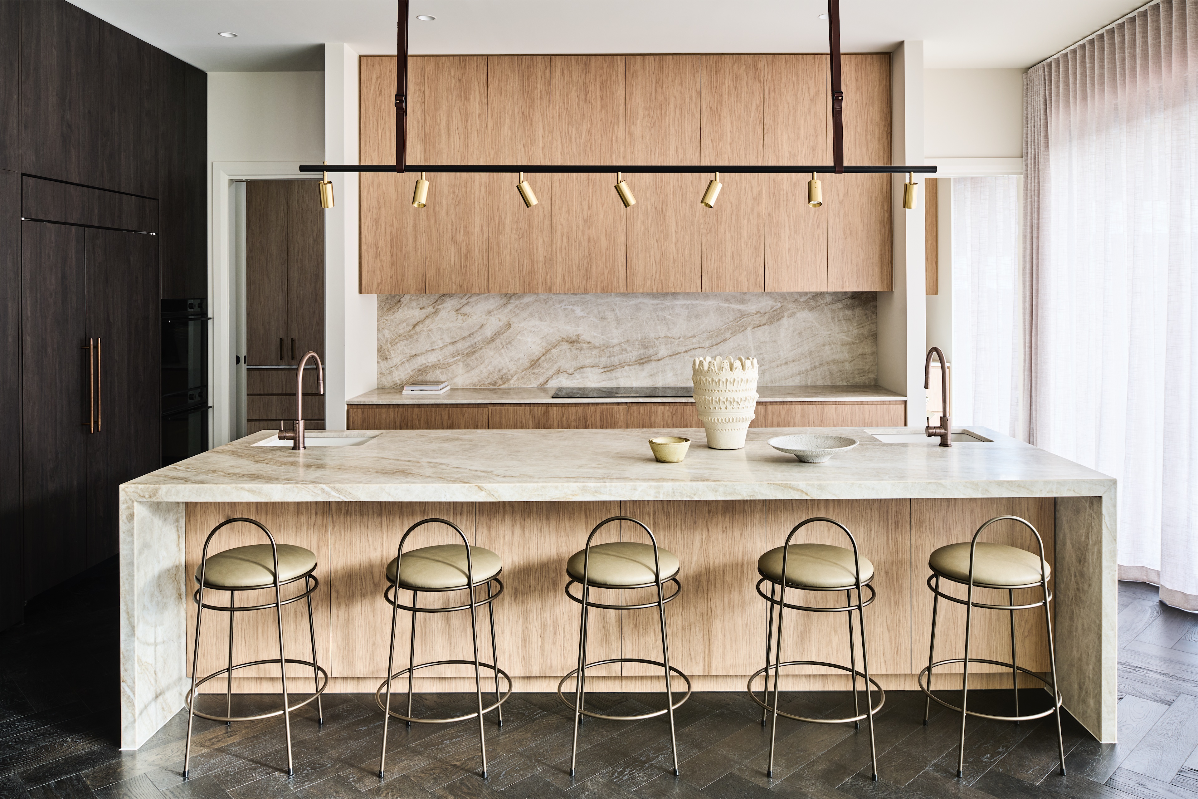 kitchen with veined stone waterfall island, timber cabinetry and brass spotlight rail, opus 5, caulfield north