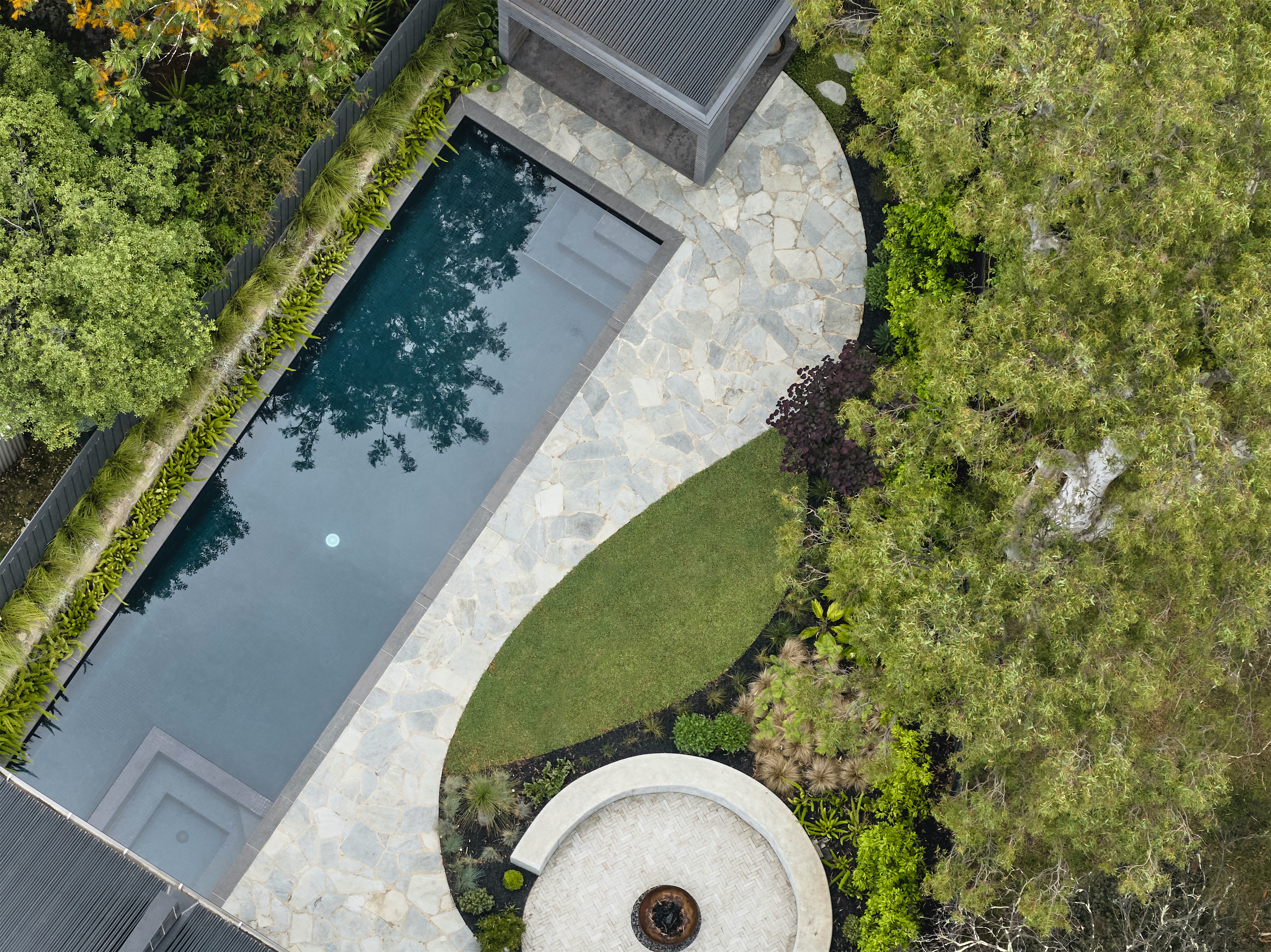 aerial view of the garden with lap pool, stone paving, curved lawn and circular fire pit, opus 2, ashburton