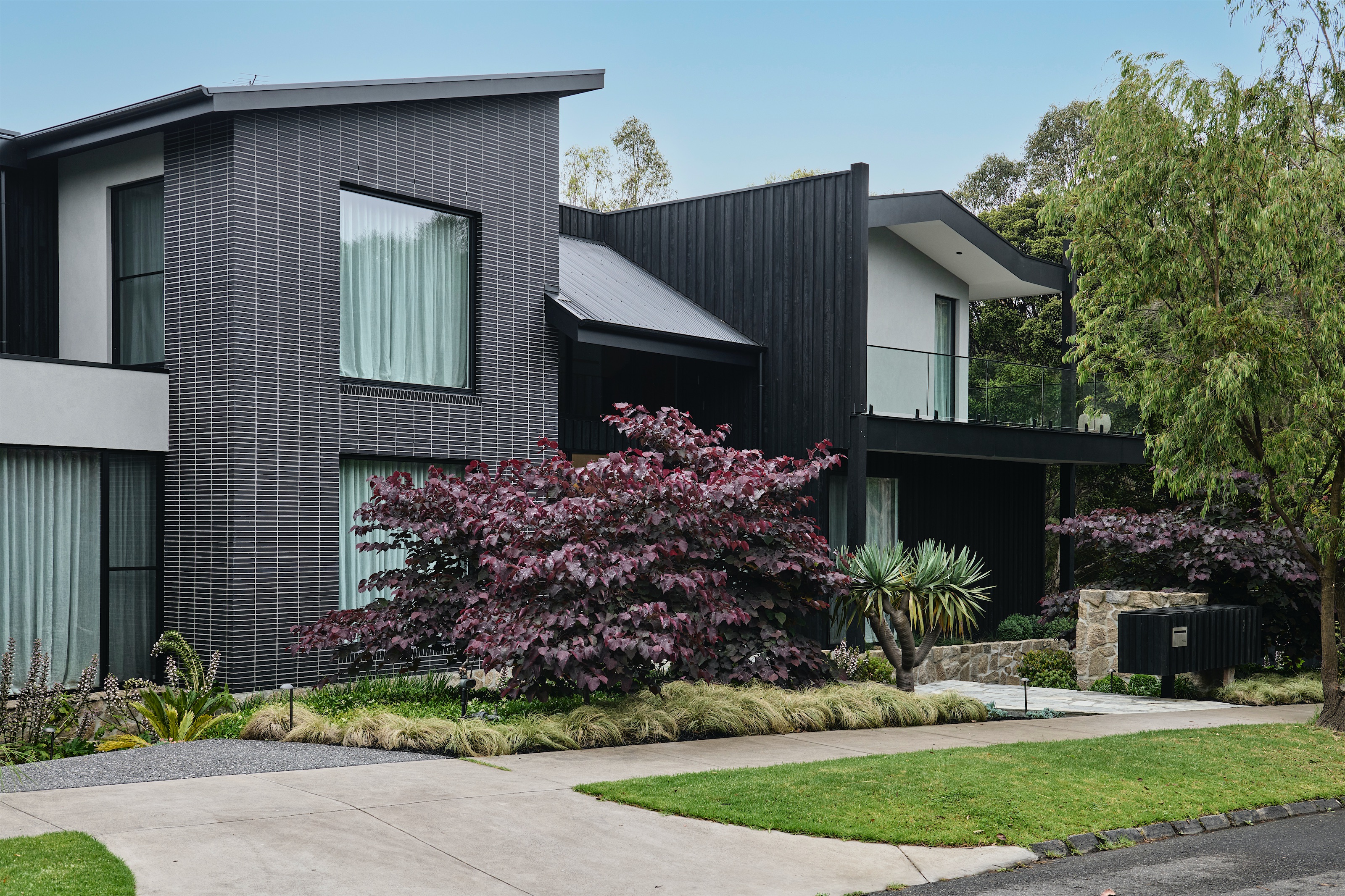 street facade in charcoal brick and black vertical cladding with a landscaped front garden, opus 2, ashburton