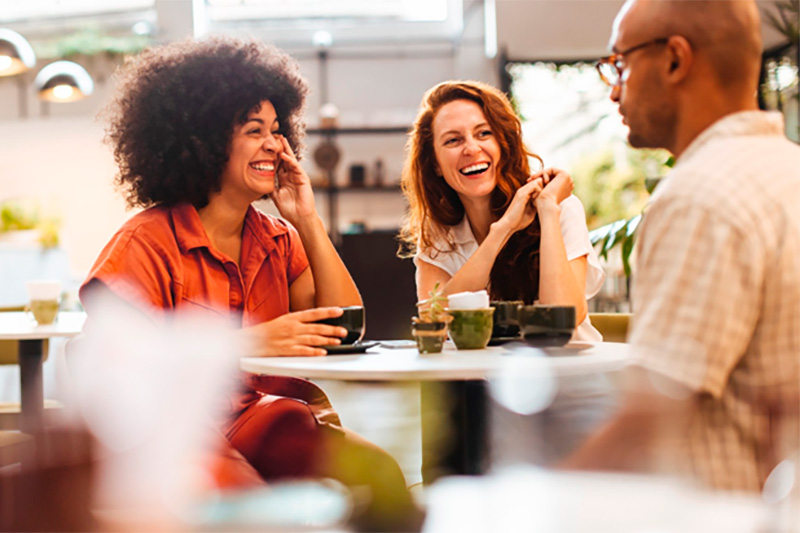 Pessoas jovens conversando alegremente sentadas à mesa