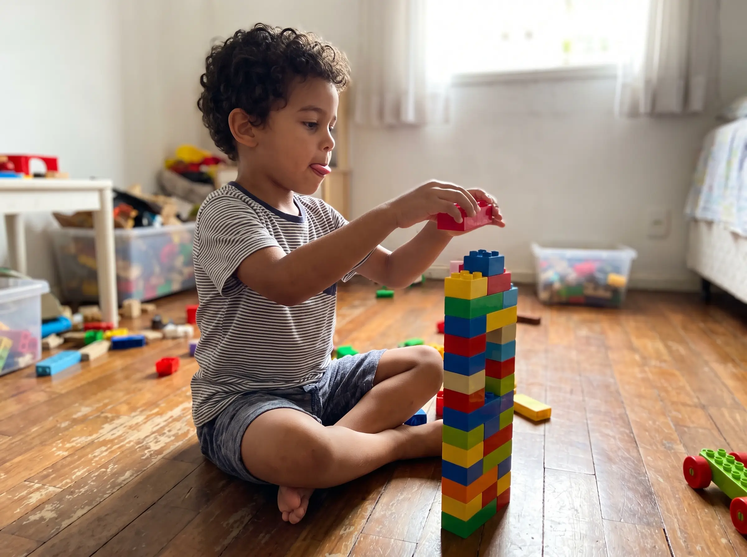 Menino montando uma torre de blocos coloridos