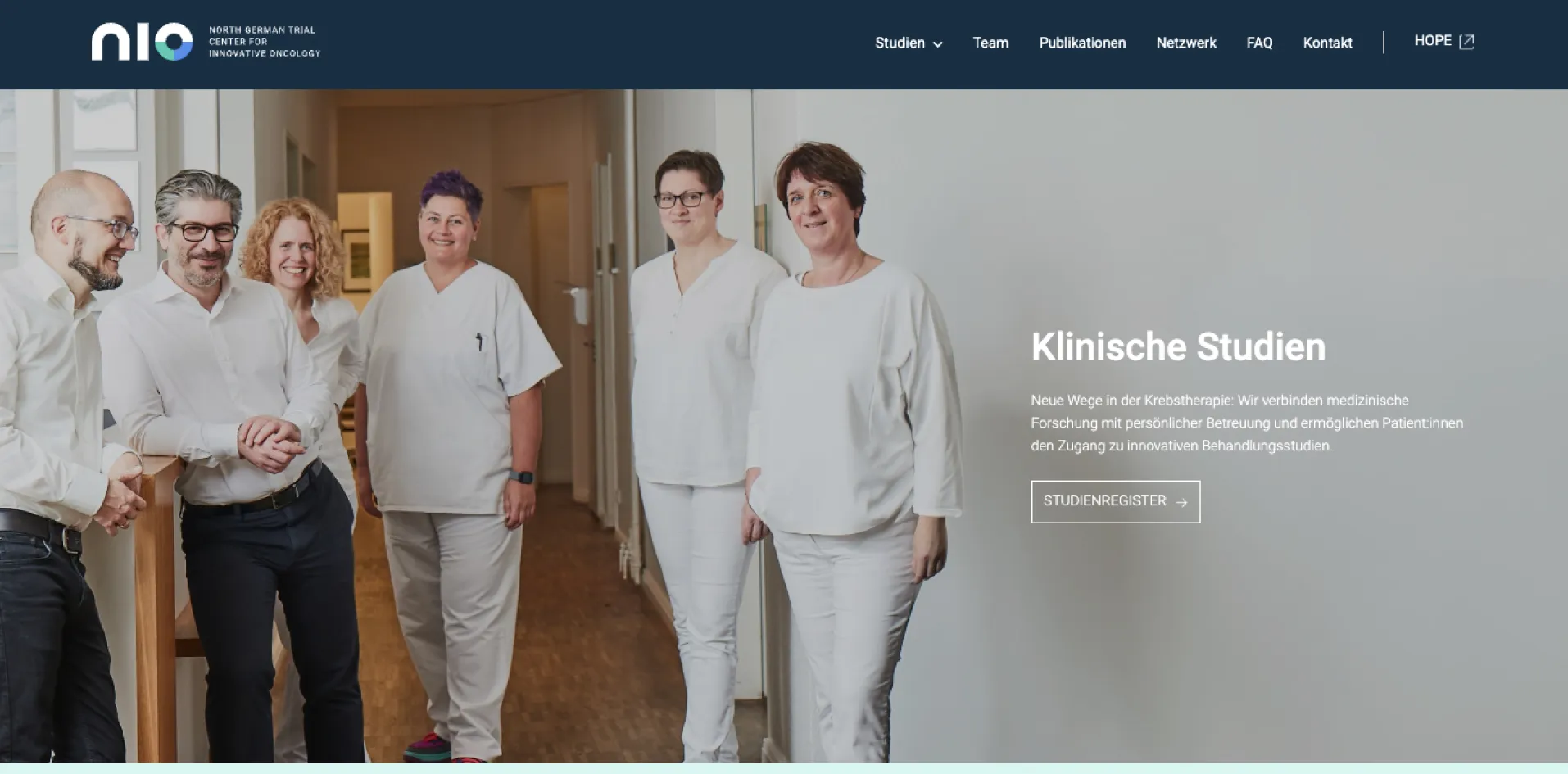 Sechs Personen, darunter medizinisches Personal in weißen Kitteln, lächeln in einem Flur, daneben Text über klinische Studien und einen Button zum Studienregister.