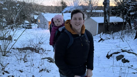 Caleb Walker walks with his child on his back outdoors