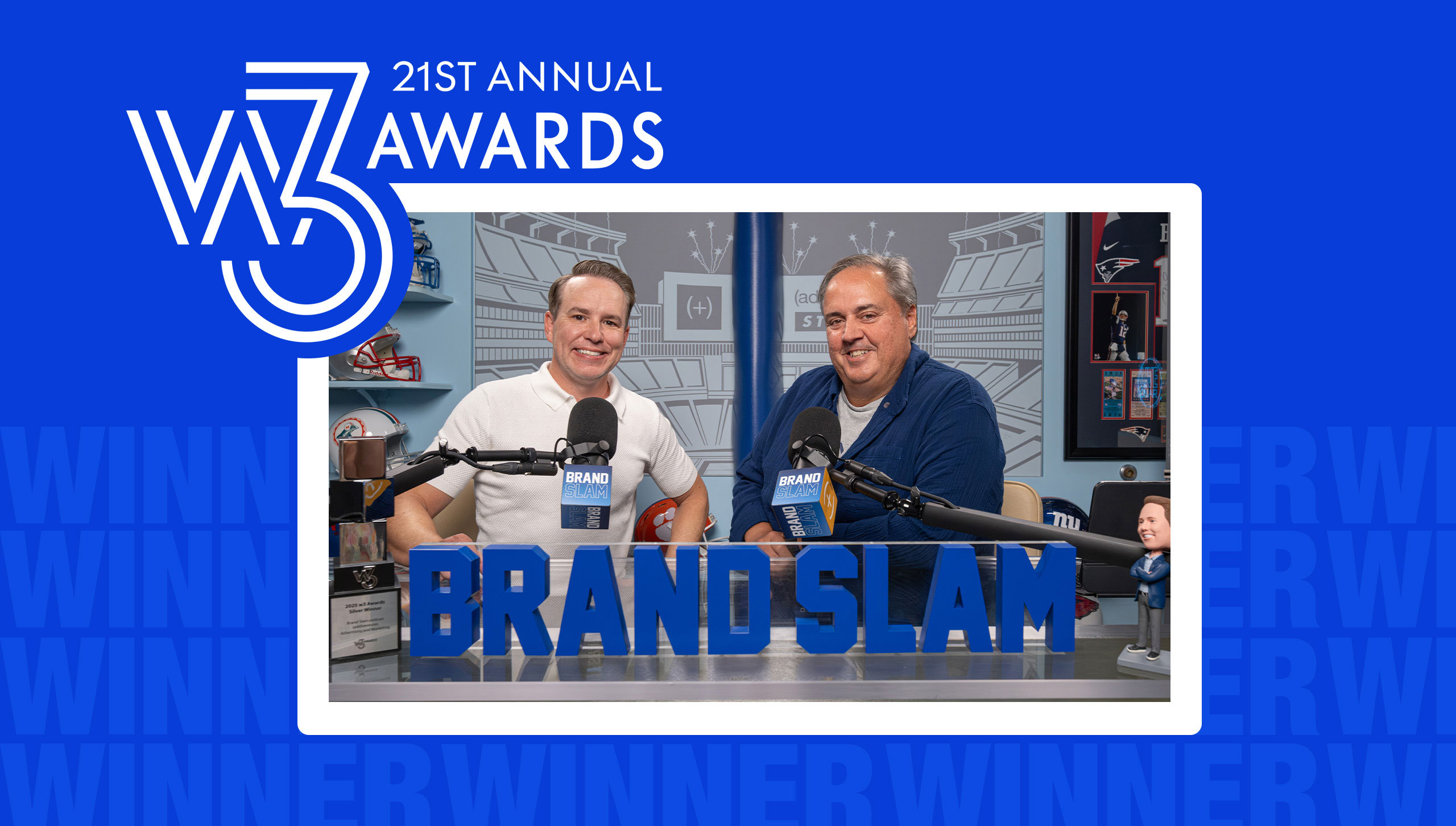 Two Brand Slam podcast hosts seated behind microphones, celebrating a win at the 21st Annual W3 Awards.