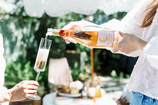 Pouring Luna Nuda Prosecco Rosé into a flute glass at an outdoor garden toast