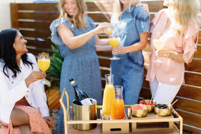 Friends toasting with orange-hued Prosecco cocktails at an outdoor self-serve drink cart