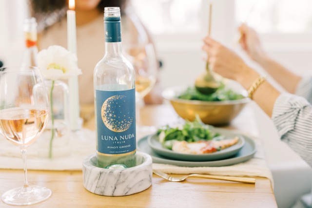 Candlelit dinner table with a bottle of Luna Nuda Pinot Grigio next to a fresh salad