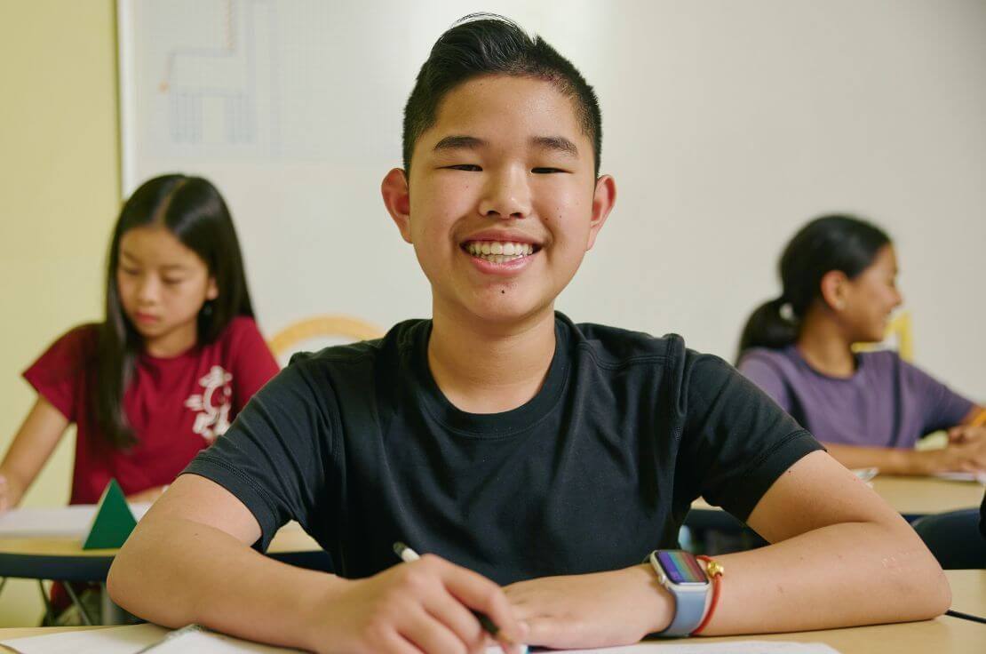 Students smiling at their desks in a Russian School of Mathematics classroom