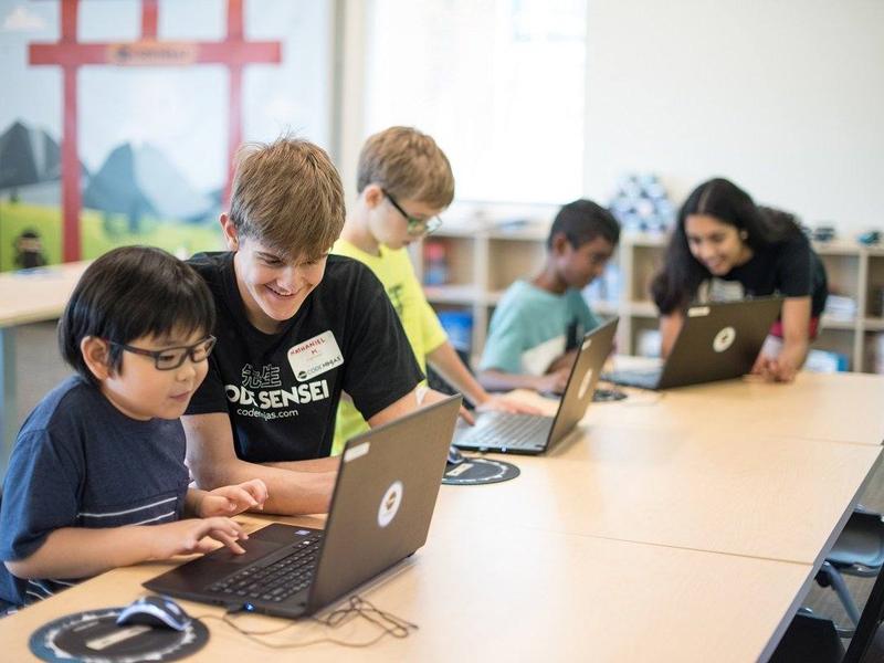 A Code Ninjas instructor helping a student with a laptop in Pleasanton, California