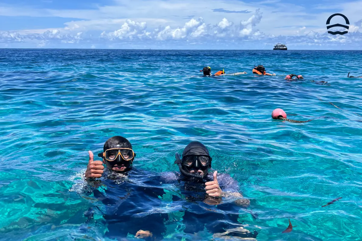 Family enjoying a snorkeling stop with Andaman Surprise, overlooking turquoise water and limestone islands under a clear blue sky on a Phi Phi Islands tour.