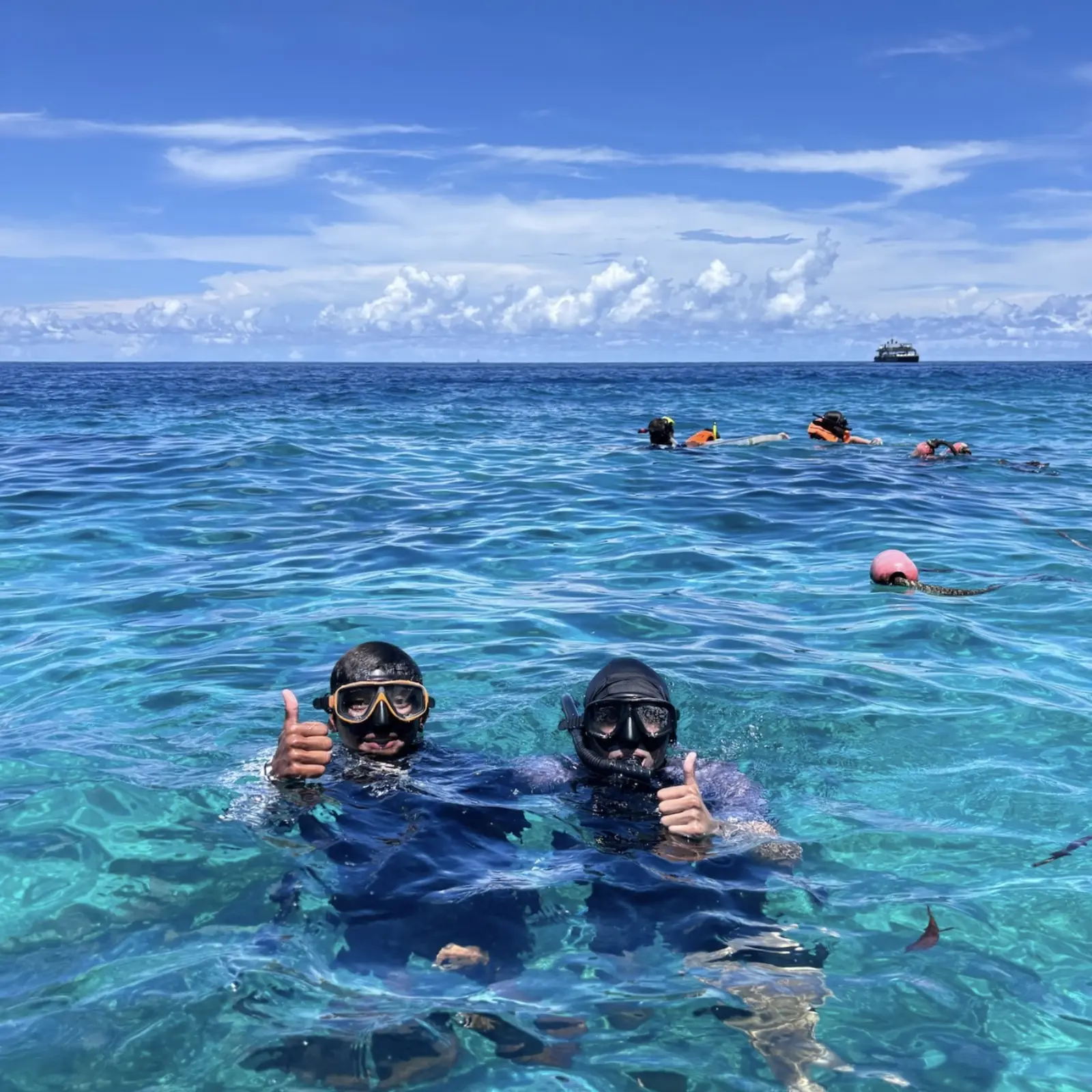 Family enjoying a snorkeling stop with Andaman Surprise, overlooking turquoise water and limestone islands under a clear blue sky on a Phi Phi Islands tour.
