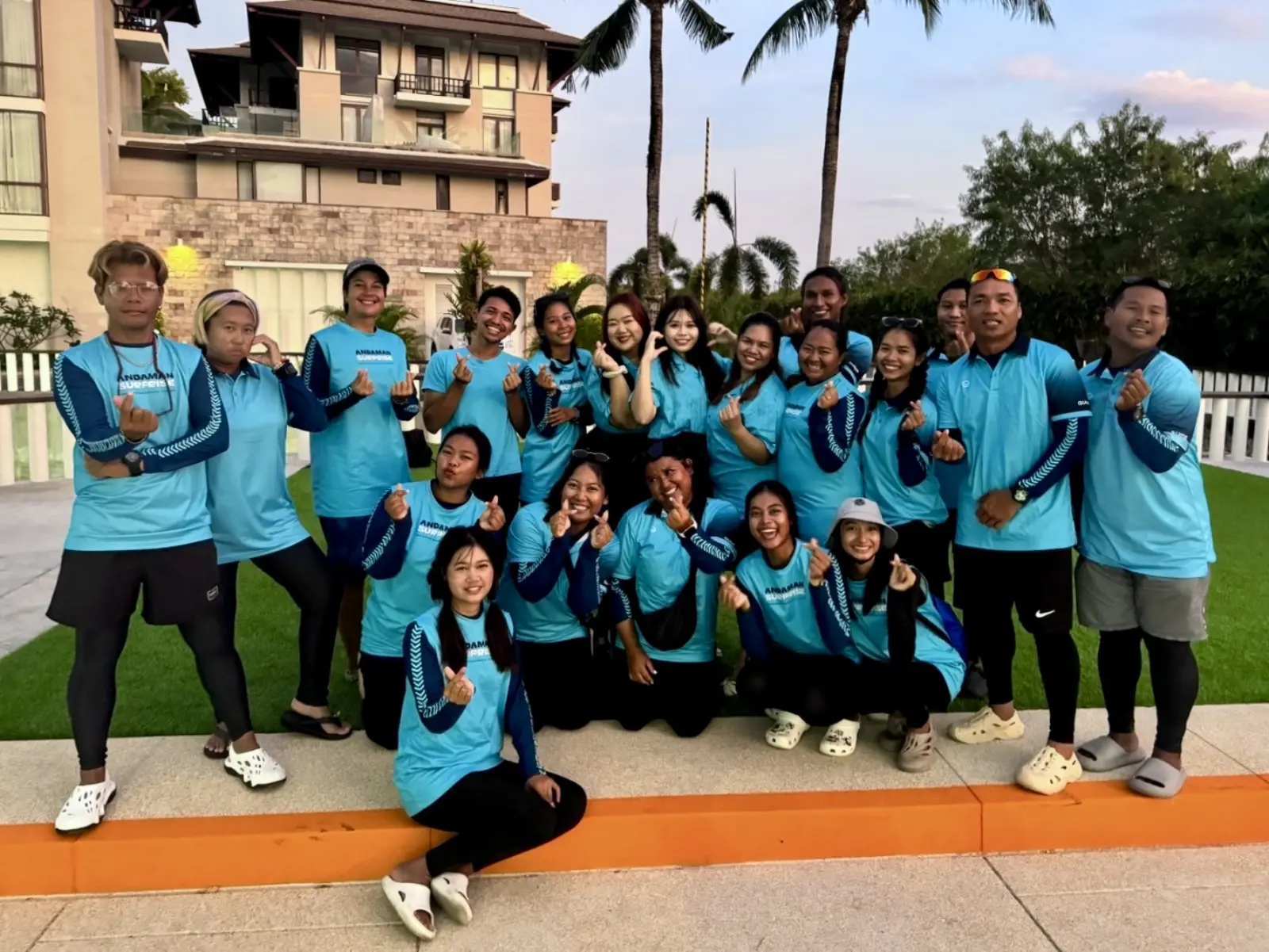 Andaman Surprise crew posing together in matching blue uniforms at a tropical resort in Thailand.