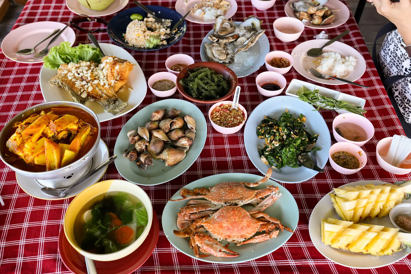  Thai seafood feast with steamed crabs, oysters, shellfish, fish, curry, vegetables, rice, and dipping sauces served family-style.