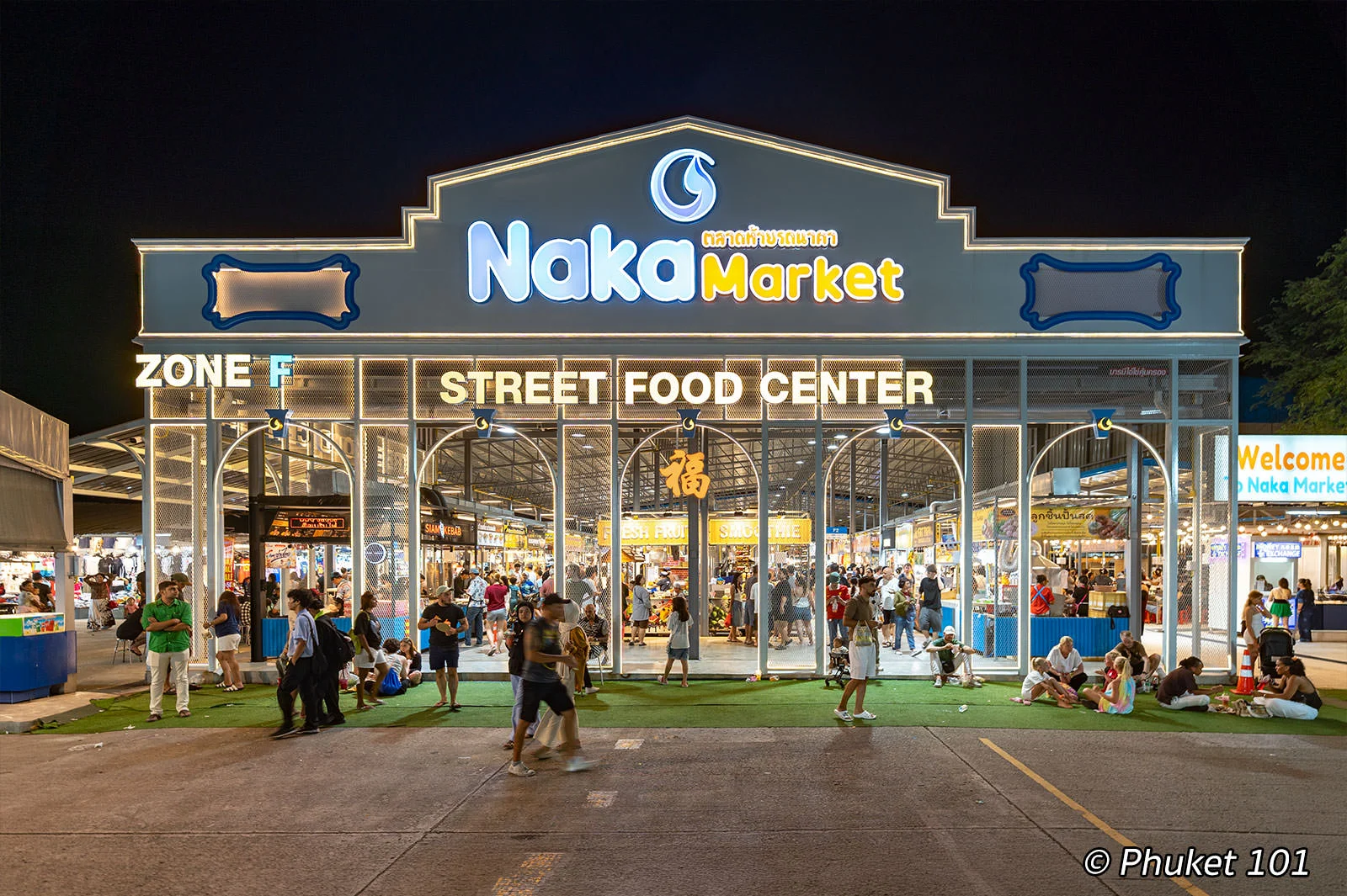 Naka Market in Phuket at night, with the illuminated street food center entrance, food stalls, and visitors exploring the night market.