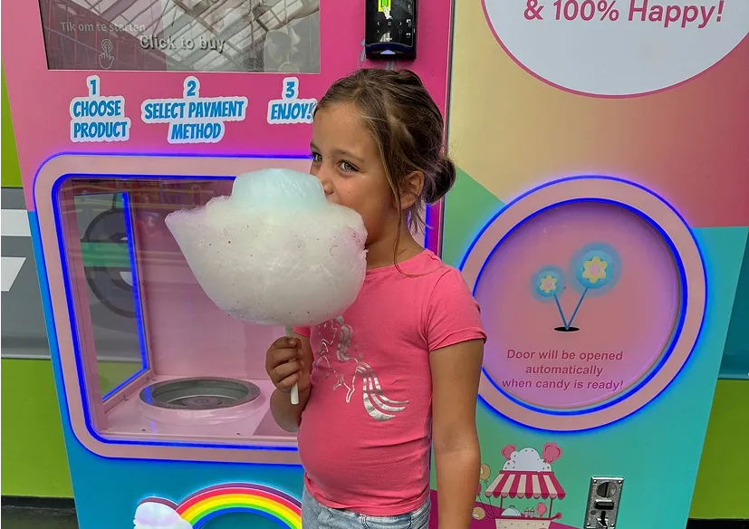 Girl enjoying fresh cotton candy in front of a Vend-Me vending machine