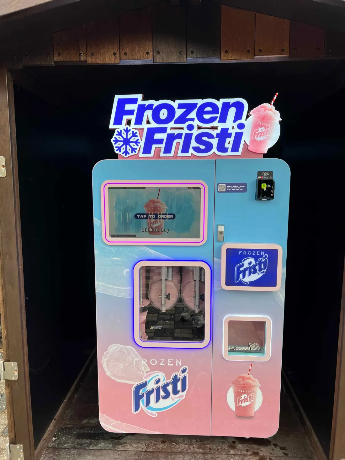 Frozen Fristi-slushautomaat van Vend-Me met verlicht bord, onder een houten dak
