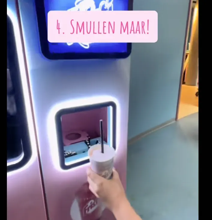 Gast pakt een verse Frozen Fristi uit het uitgifteluik van de machine