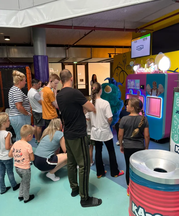Parkmaskottchen und Kinder an einem Vend-Me Zuckerwattestand in einem Indoor-Spielpark