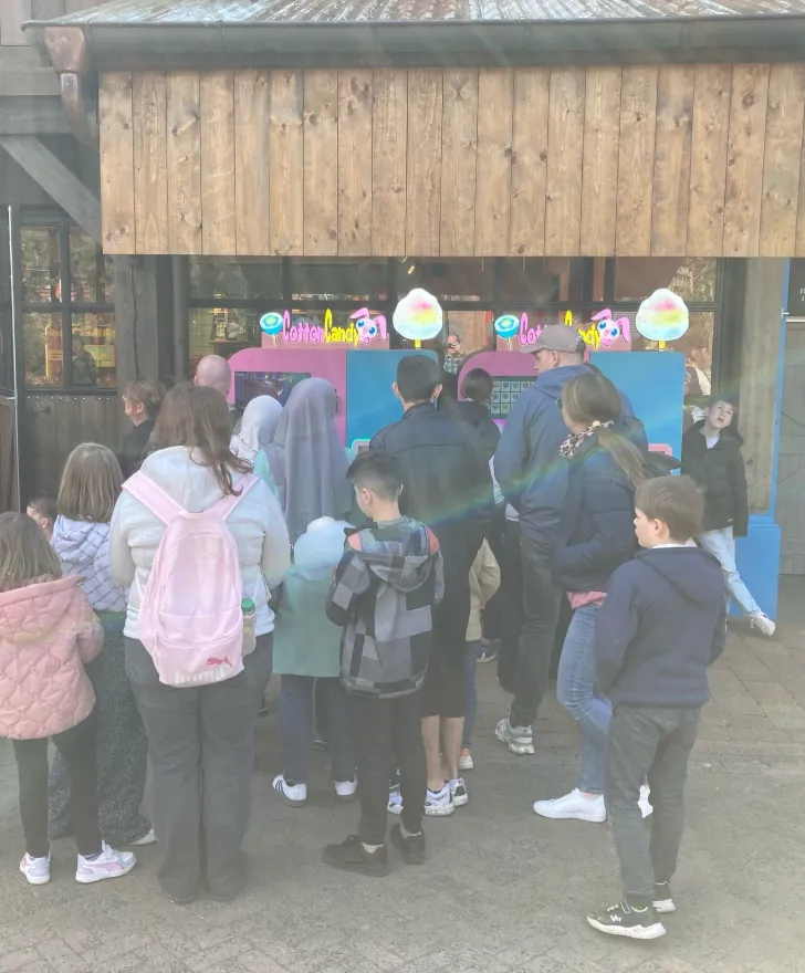 Familien schauen an zwei Vend-Me Zuckerwatteständen in einem Freizeitpark zu