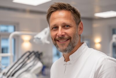 Smiling male dentist wearing white coat in a modern dental clinic.