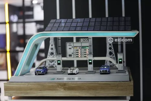 Miniature model of Exicom Harmony Boost solar-powered EV charging station with three model cars and BESS energy system display