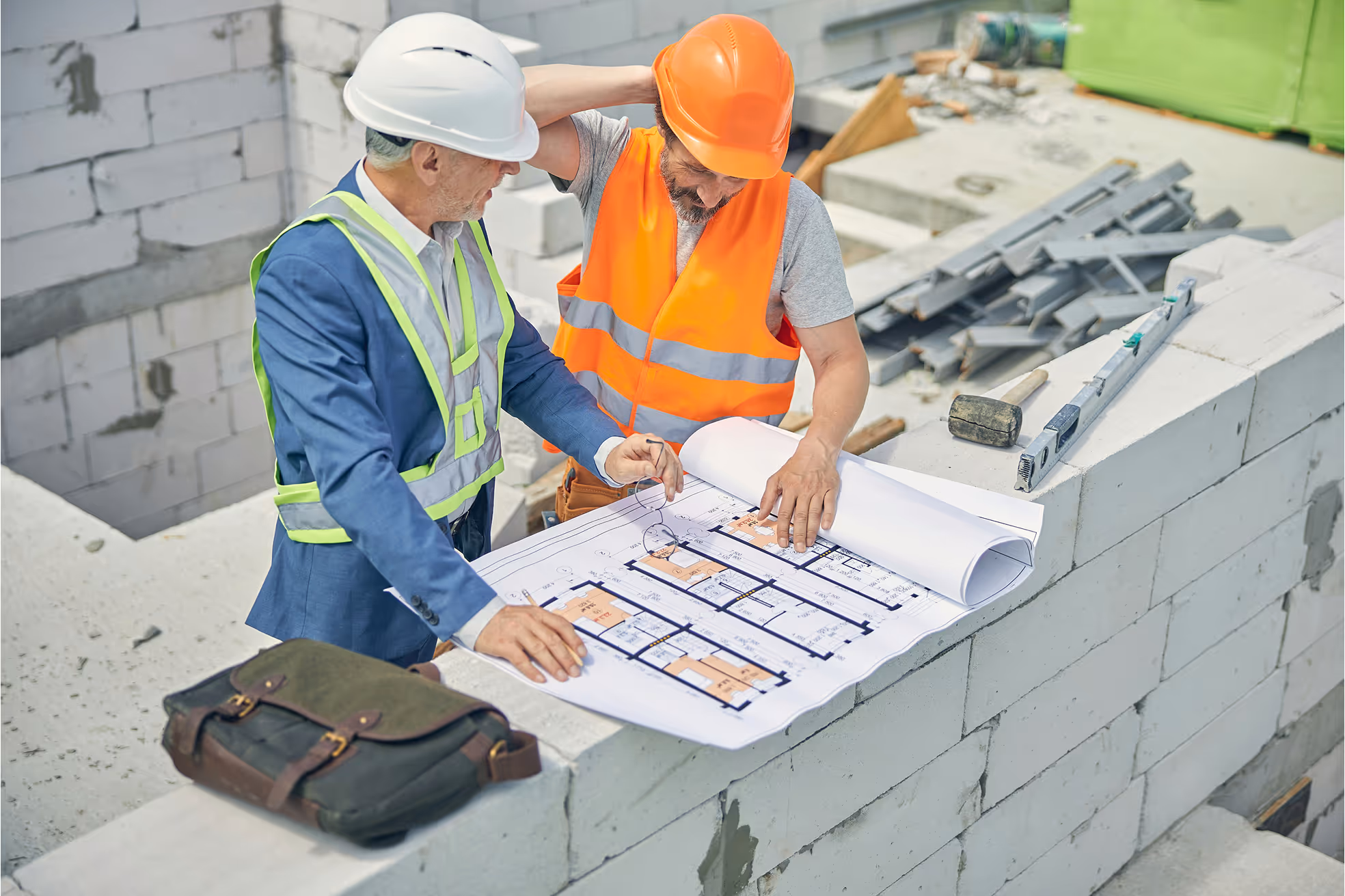 Engineers reviewing blueprints at construction site.