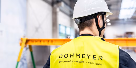 Dohmeyer assembly workshop employee standing with his back towards the camera, safety vest reads Dohmeyer