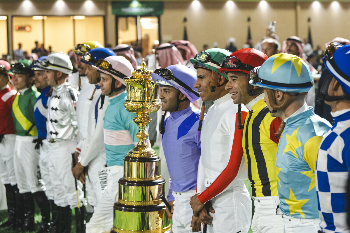 Jockeys standing together with trophy