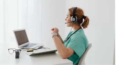 Medizinische Fachangestellte, welche am Laptop mit Kopfhörern telefoniert