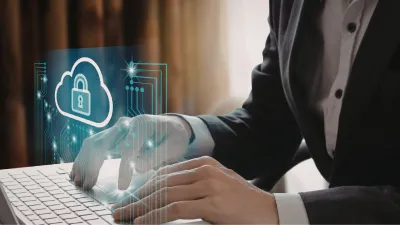 Mensch am Laptop mit Security Zeichen über dem Laptop