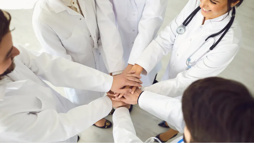 Ärzt:innen Gruppe, die Ihre Hände in die Mitte tun
