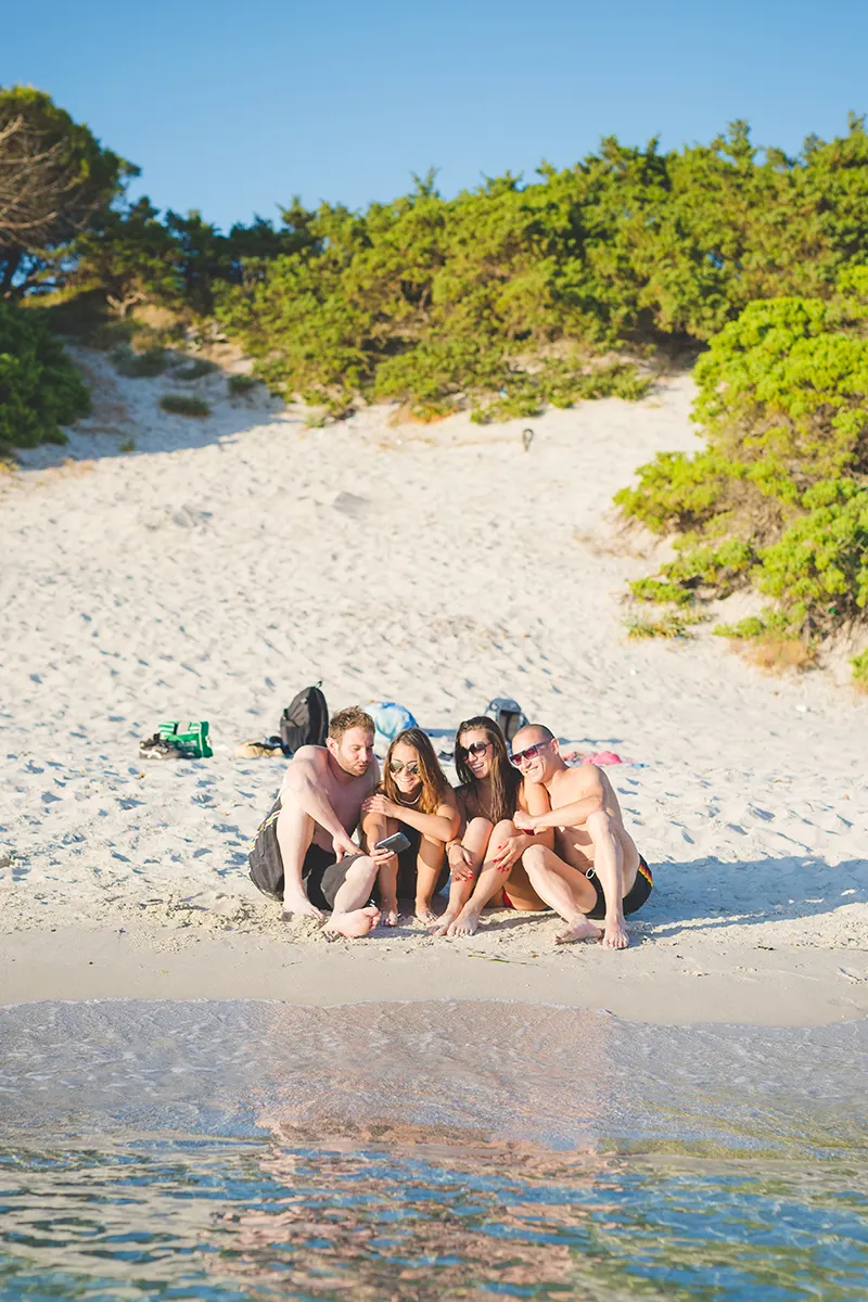 Zwei Pärchen chillen am Strand in der Sonne.