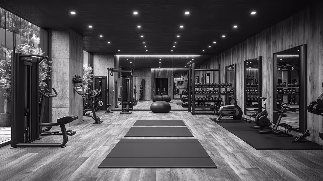 Modern gym interior with exercise mats, weight machines, dumbbells, and large mirrors along wood-paneled walls.