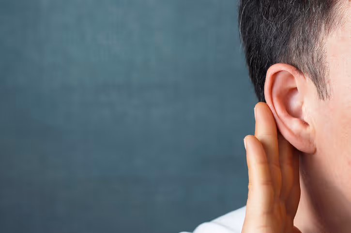 The man listens attentively with her palm to her ear, close up
