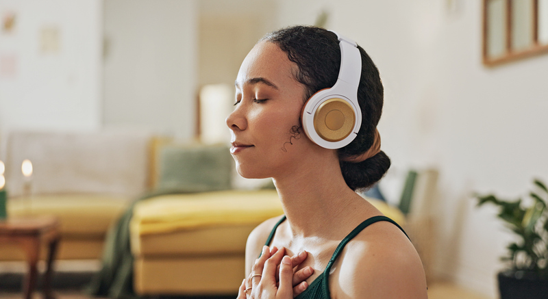 A woman meditates through headphones with calming music in the living room.jpg