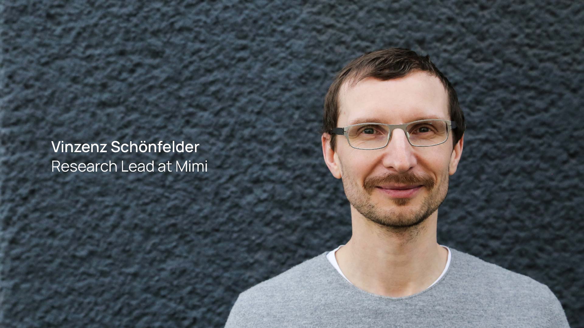 Vinzenz Schönfelder, Research Lead at Mimi, smiling in front of a textured grey wall