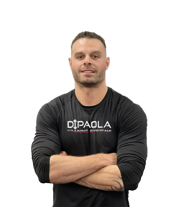 Ben Dipaola gym with short hair, wearing a black long-sleeve shirt that says "DiPaola Training Systems." He stands confidently with arms crossed.