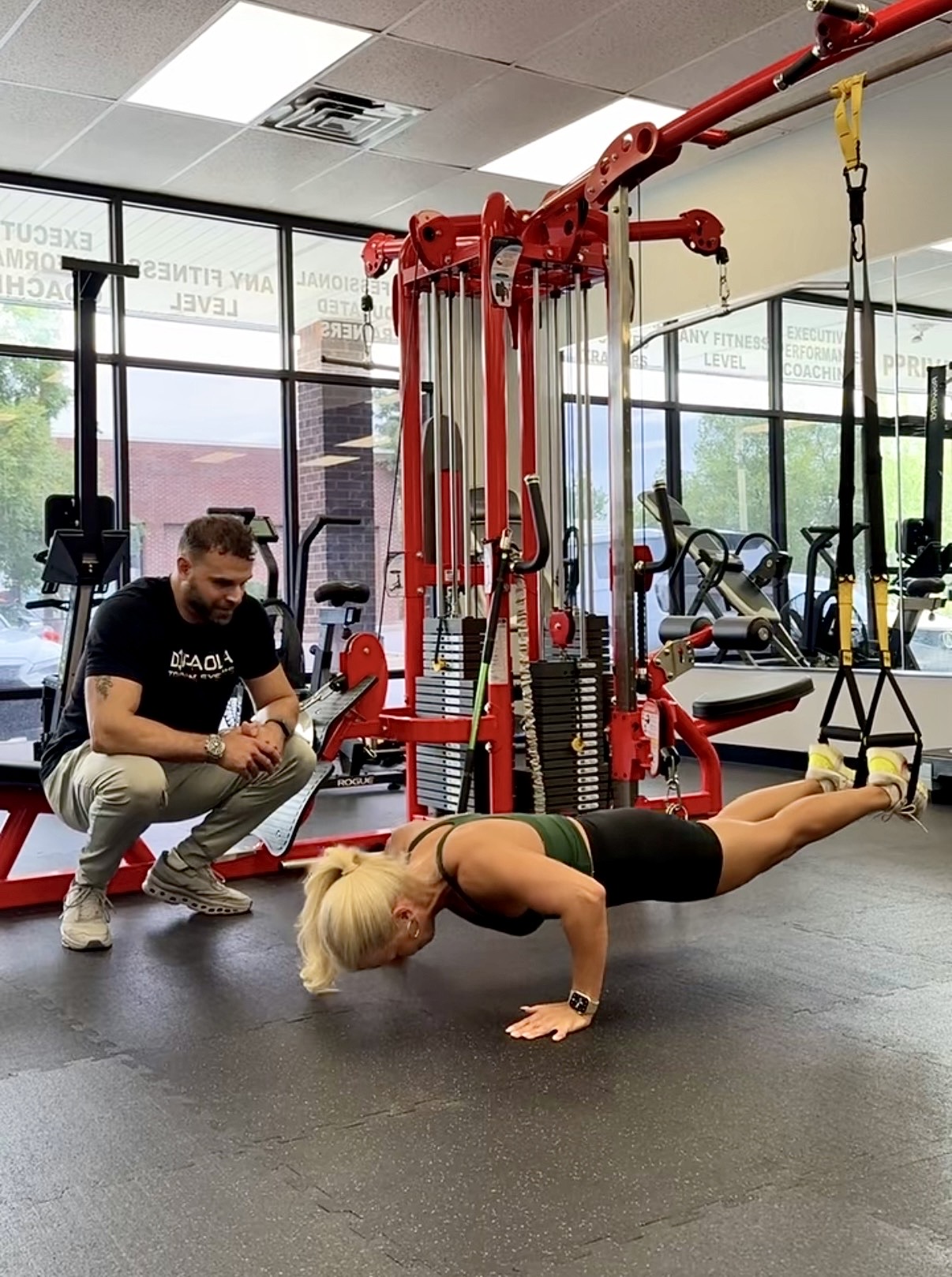 A personal trainer actively coaches a client through a challenging set of suspension push-ups at a private gym in Lexington, Kentucky, guiding hand position, breathing, and tempo to maximize results and prevent injury