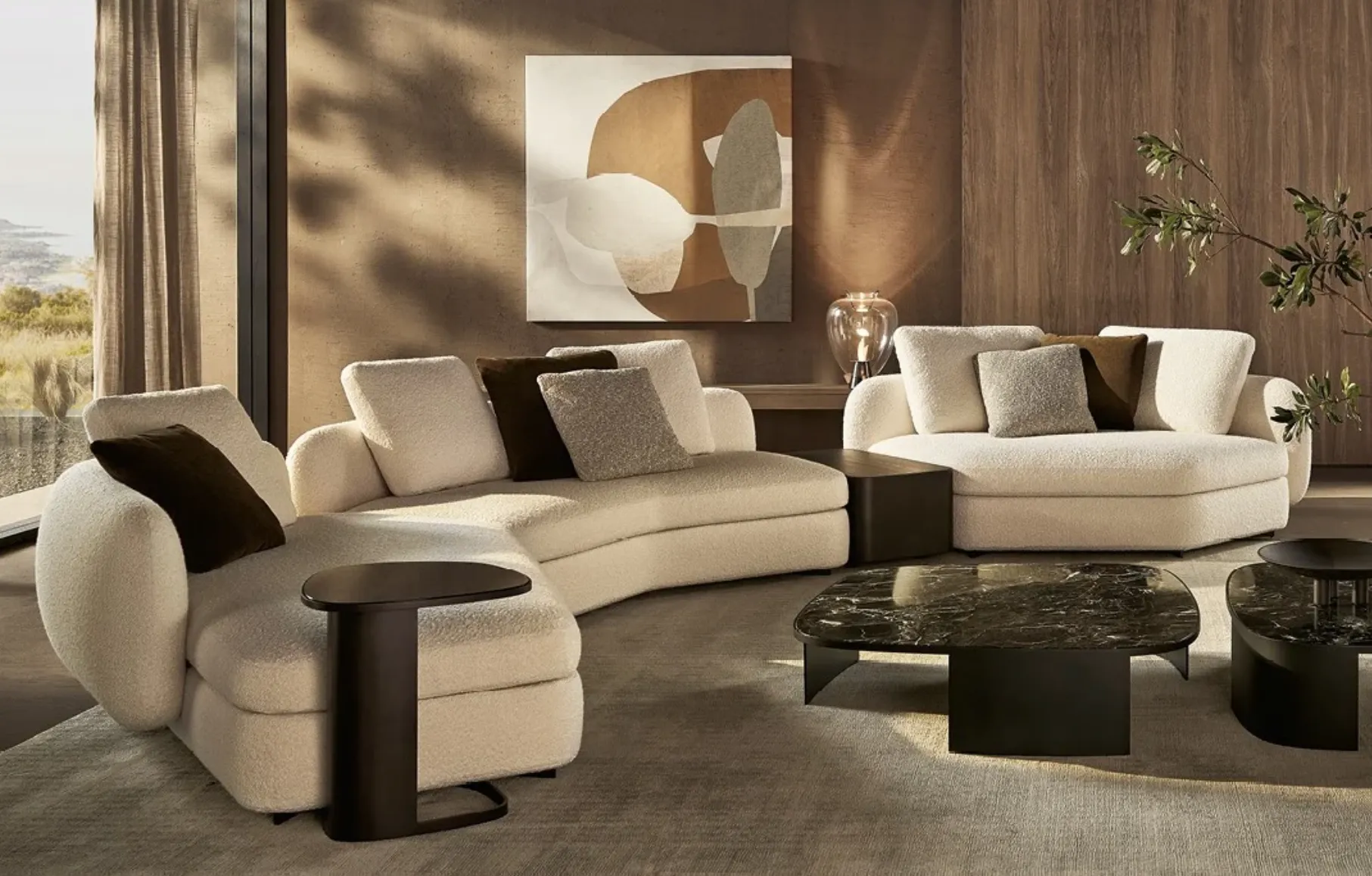 Modern living room with curved white sofas, brown cushions, black marble coffee tables, and abstract wall art.