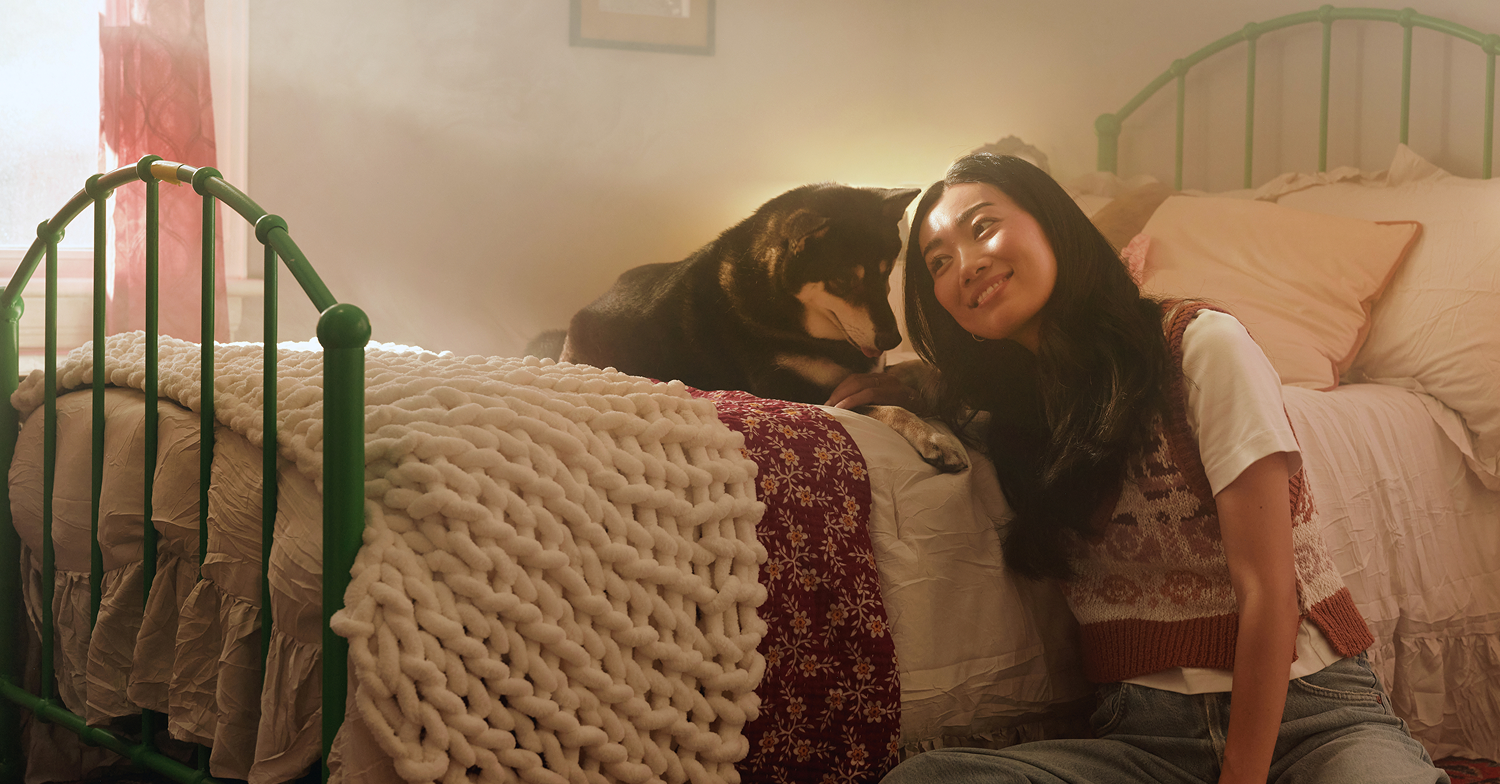Red-haired woman working on a laptop at a table with a Dalmatian dog sitting beside her.