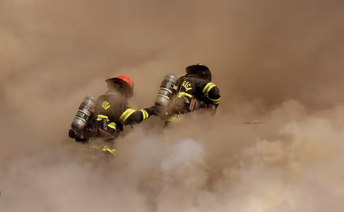 Two firefighters walking through smoke