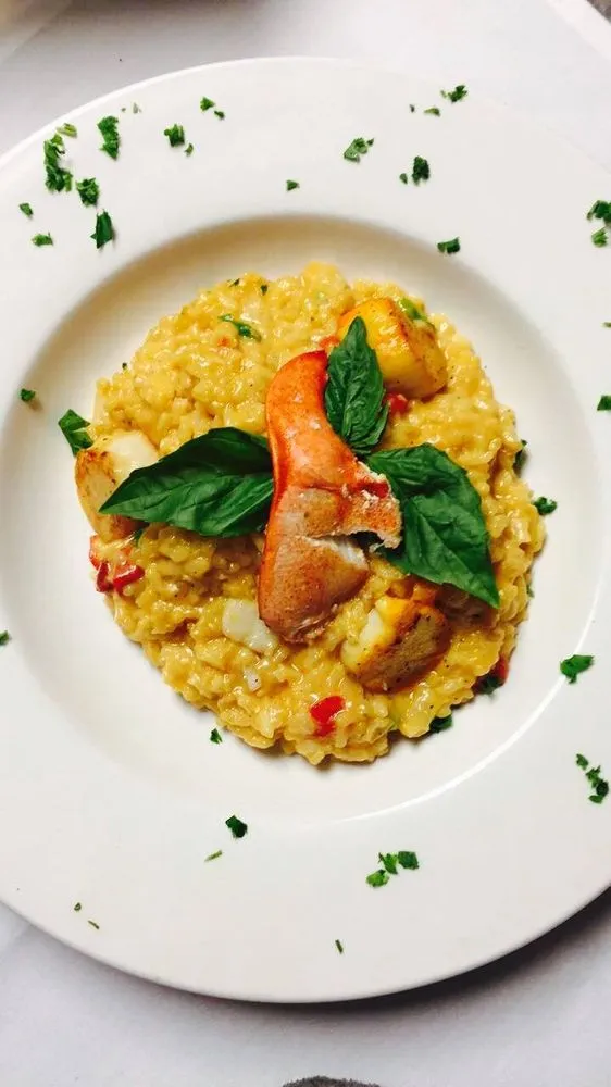 A plate of creamy risotto topped with succulent shrimp and fresh basil leaves, elegantly presented.