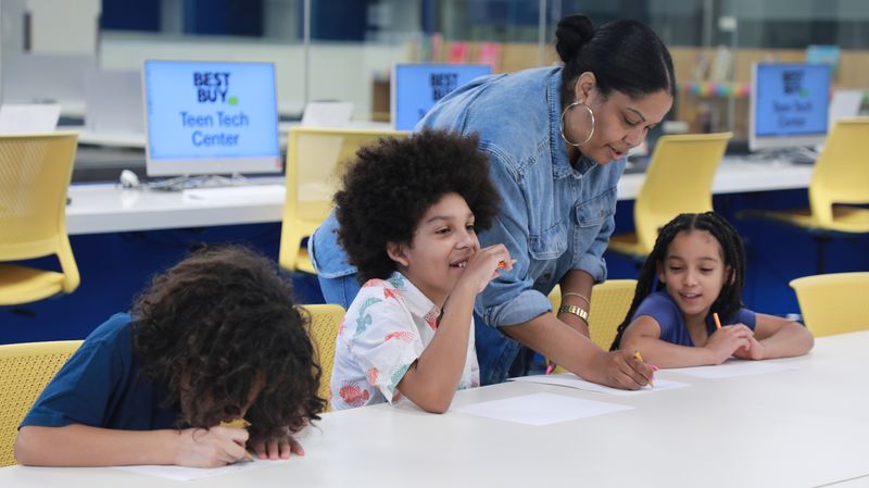 A WCT volunteer working one-on-one with a student at the Best Buy Teen Tech Center