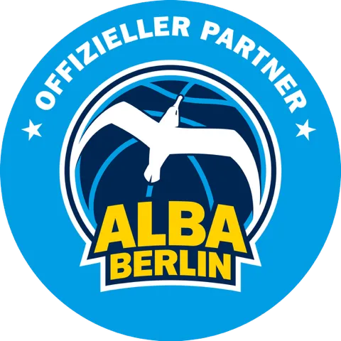 Rundes blaues Logo mit der weißen Aufschrift ‚Offizieller Partner‘ und dem weißen stilisierten Vogel über den gelben Worten ‚ALBA BERLIN‘.