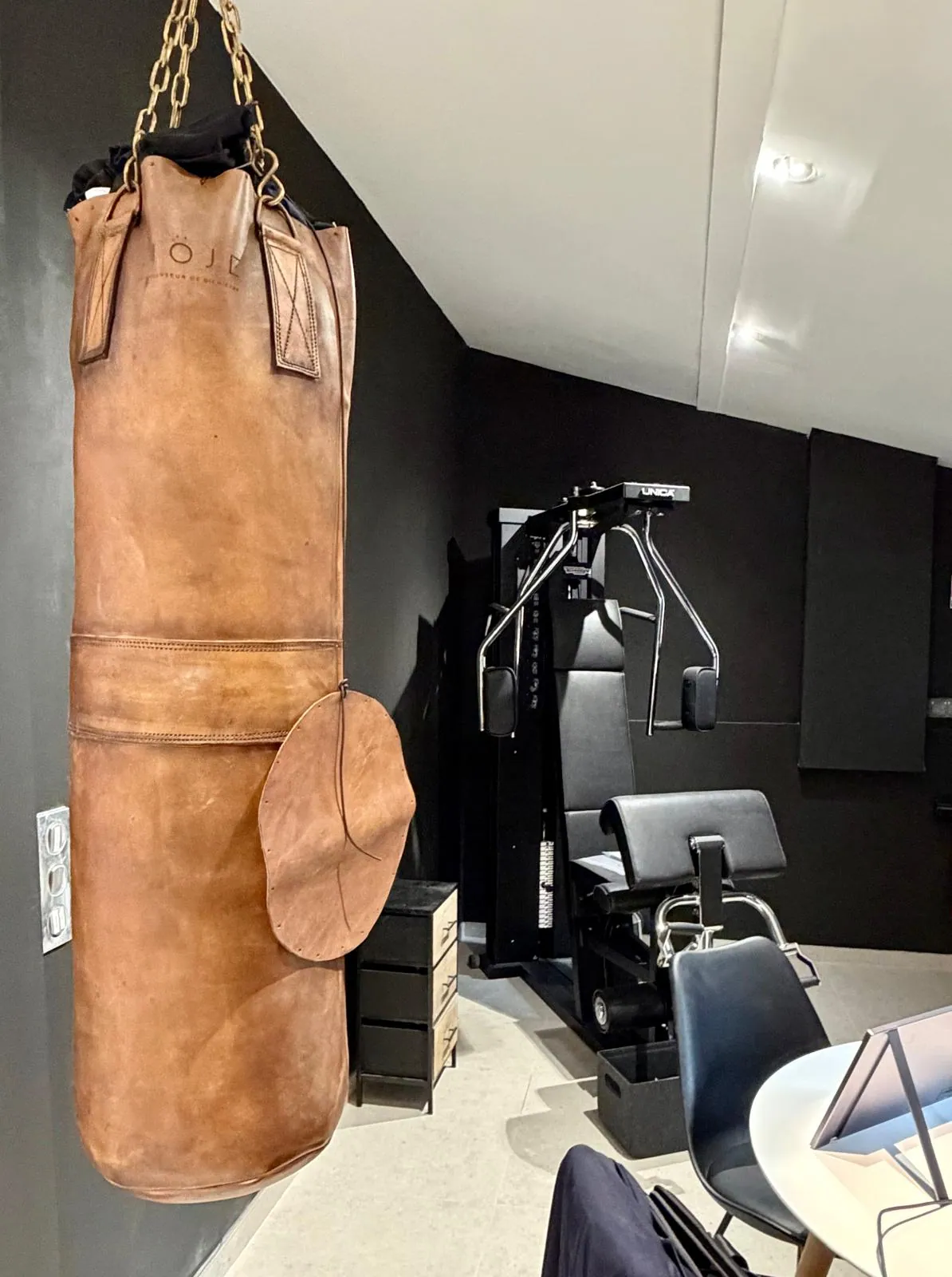 Espace fitness du showroom Nöje avec sac de frappe en cuir et poste de musculation