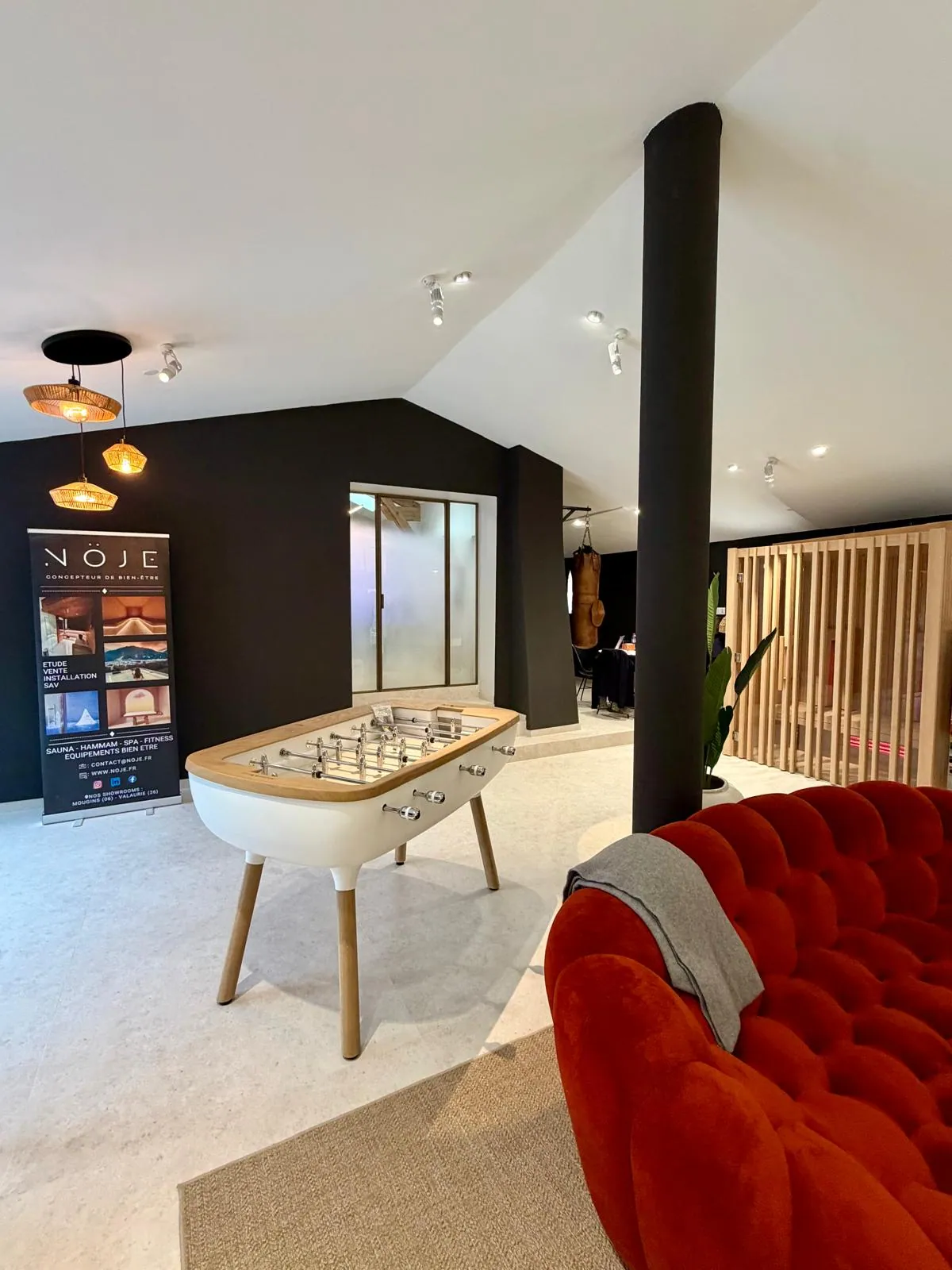 Salon d'accueil du showroom Nöje avec canapé et baby-foot en bois