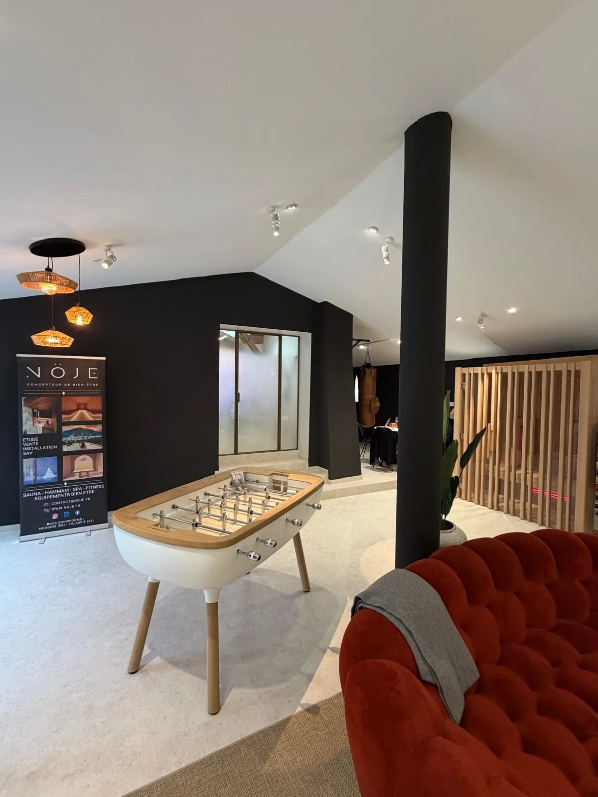 Salon d'accueil du showroom Nöje à Mougins avec canapé, baby-foot et porte d'entrée vitrée